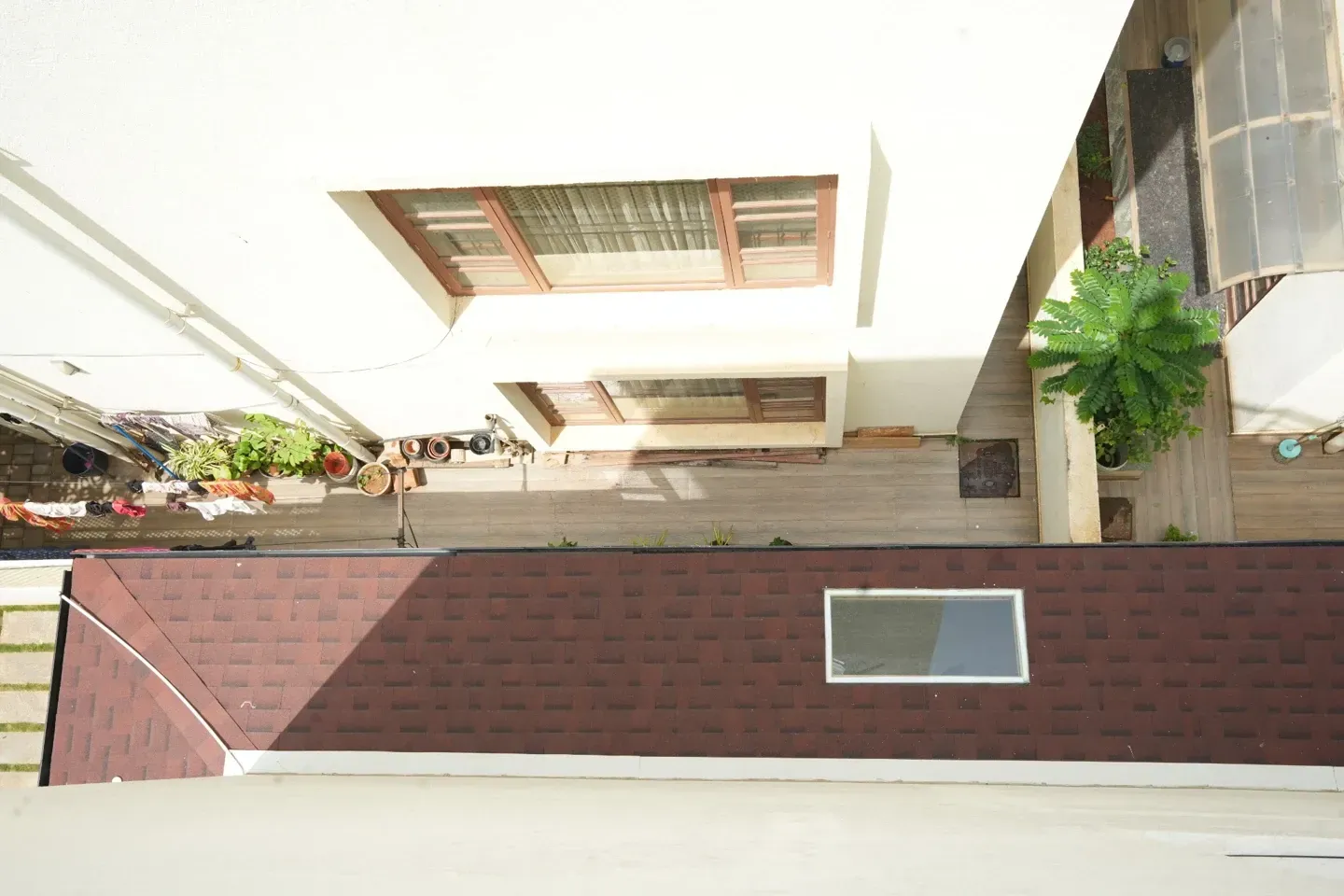 Overhead view of the long red shingles canopy with a rectangular skylight beside the villa