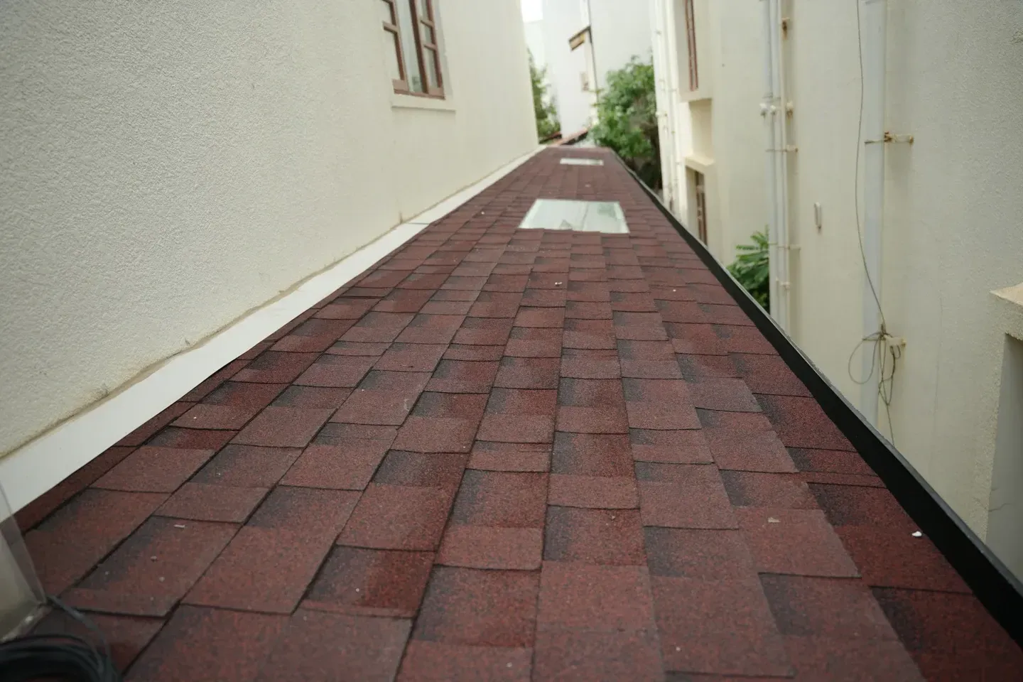 View along the red shingles roof with two rectangular skylights between the villa walls