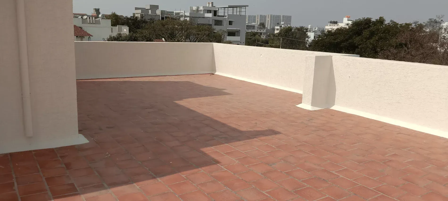 Before: open tiled terrace with white parapet walls