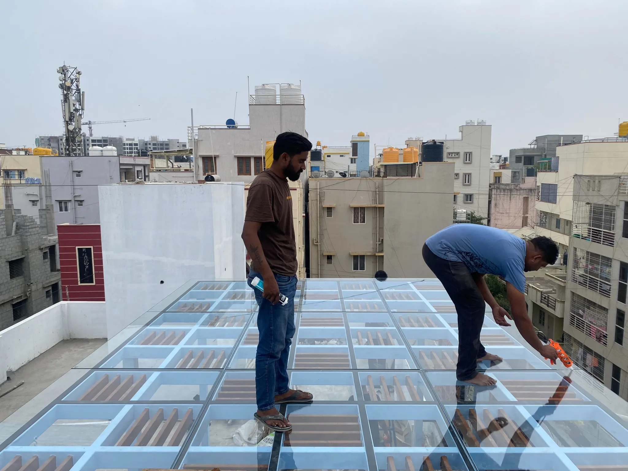 Team members carrying out maintenance on a glass pergola roof