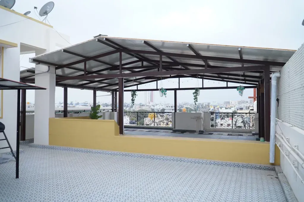 Front view of a finished PUF sheet terrace pergola showing metal beams, shaded seating space and the roof underside