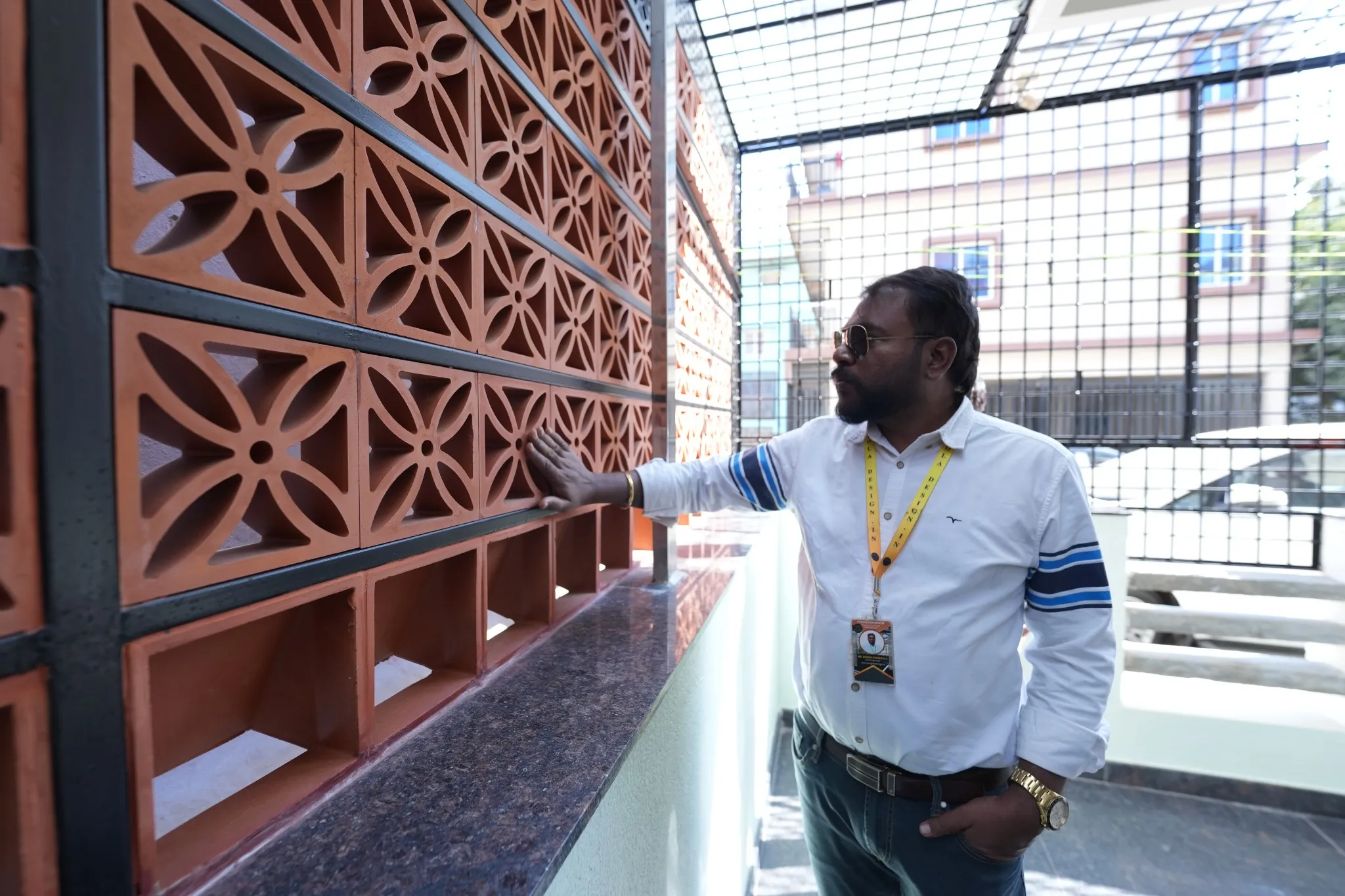 Pergola Design.in team member inspecting terracotta jali tiles fitted within a steel frame