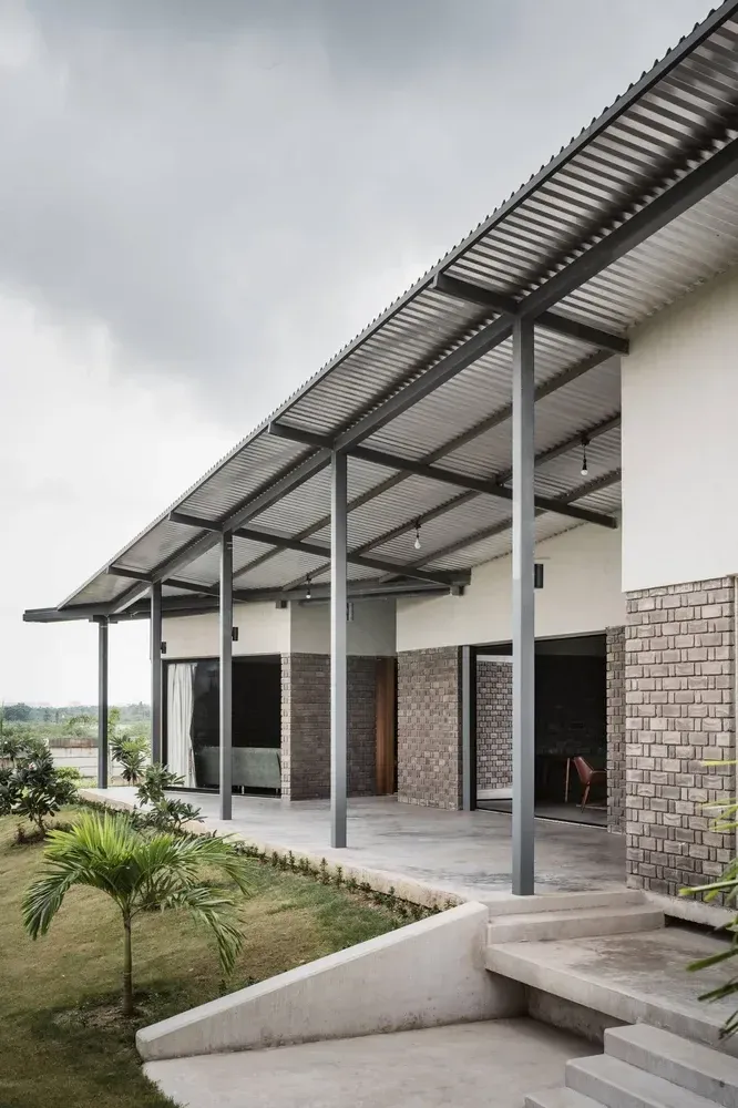 Metal-framed shade canopy covering an exterior access area beside a large building