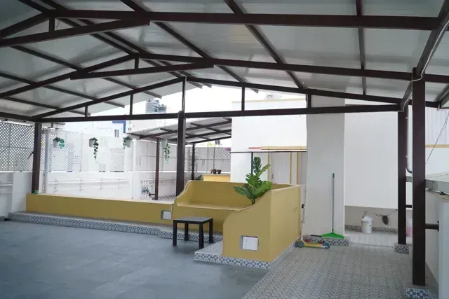 View across a sheltered terrace showing roof panels, dark beams and open floor space