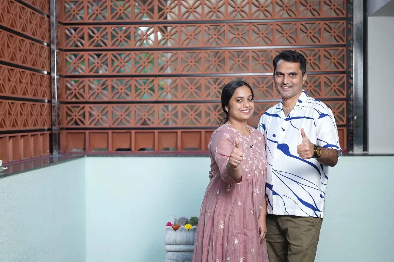 Couple standing beside a terracotta jali privacy screen