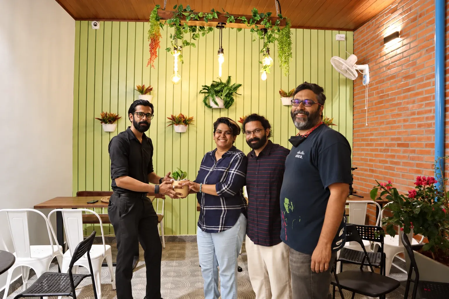 Four people gathered with a potted plant in a completed covered seating area