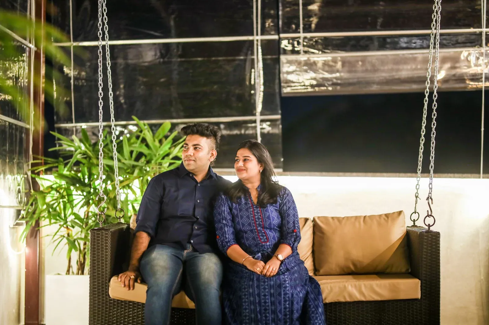 Couple seated on a suspended swing beneath a covered terrace