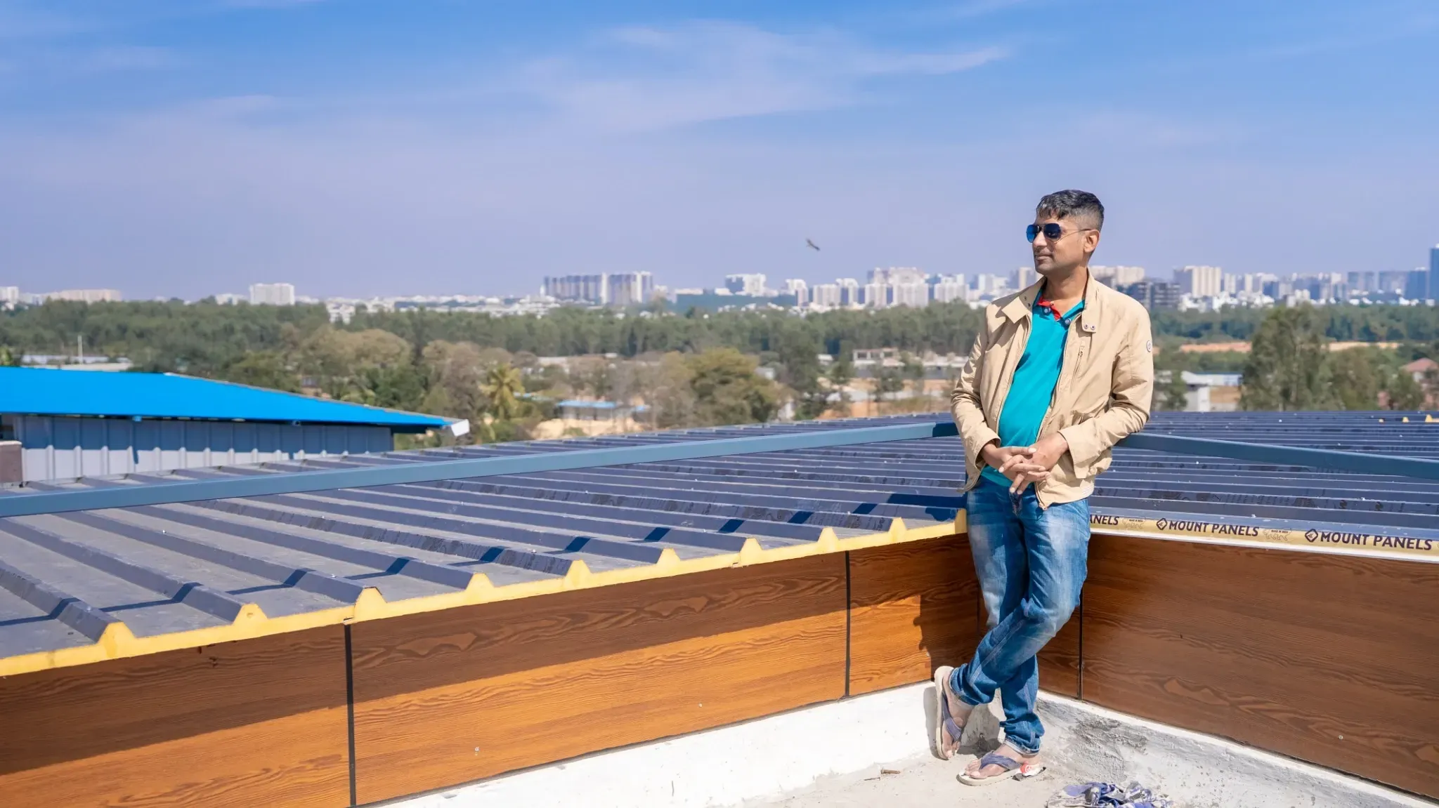 Man standing beside a completed rooftop with a city view