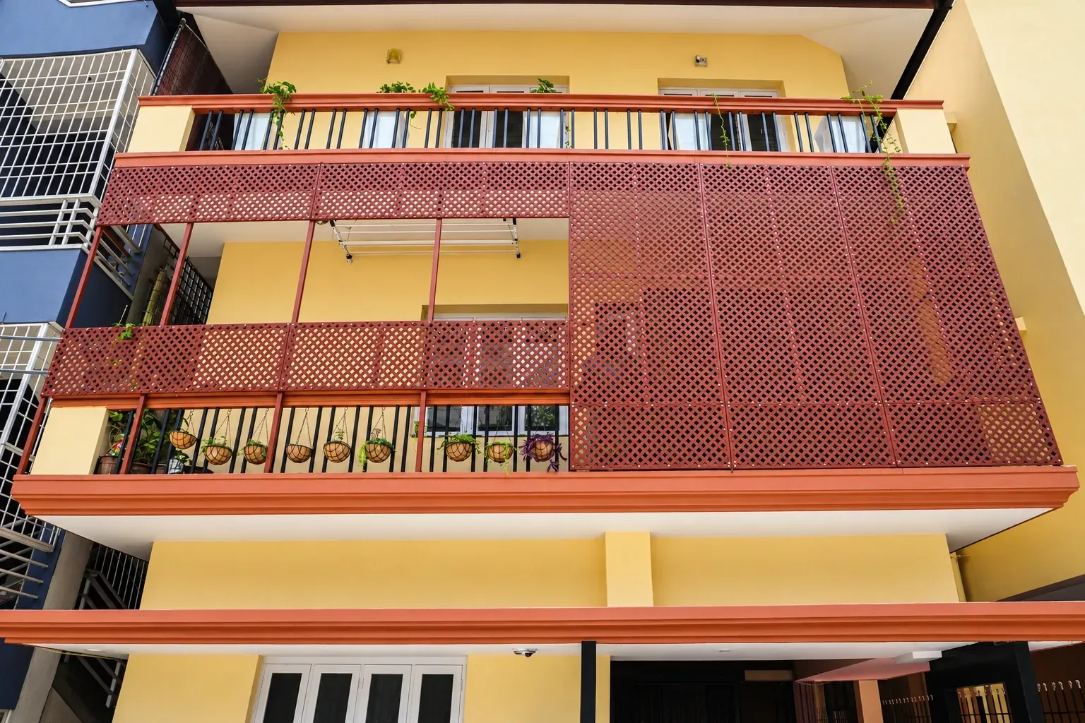 Completed building facade with terracotta-coloured privacy panels and balcony railings