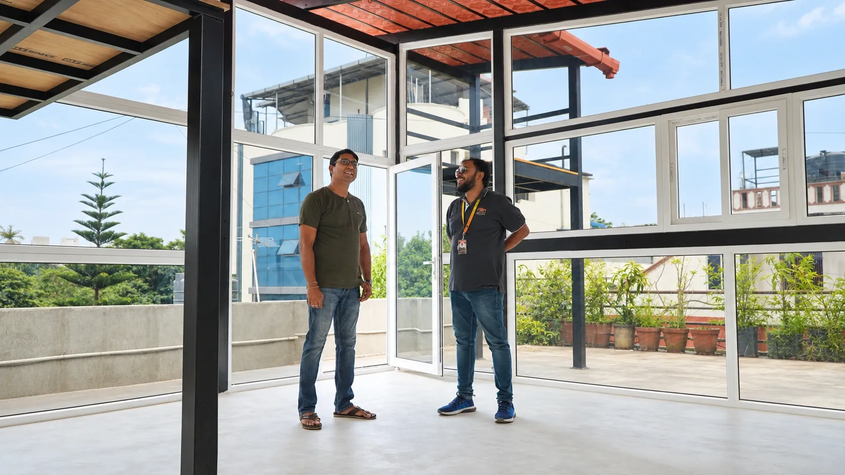 Two people standing inside a completed glass-enclosed terrace structure
